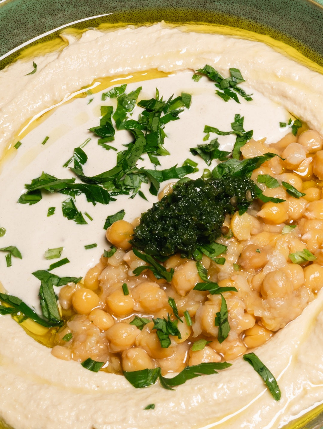 Creamy classic hummus at Mazal Shawarma & Grill, topped with whole chickpeas, parsley, and olive oil.